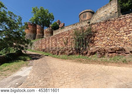 Eastern Wall Of Red Brick Triangular Fortified Castle chateau De Castelnau-bretenoux And Cobblestone