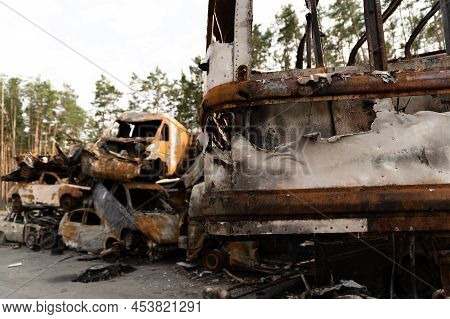 Ukrainian Man Stands Against The Background Of Broken And Burnt Cars Affected By Russian Missiles. D