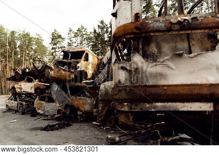 Ukrainian Man Stands Against The Background Of Broken And Burnt Cars Affected By Russian Missiles. D