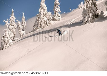 Skier Descending Down The Snowy Hill On Splitboard And Shredding Powder Snow.