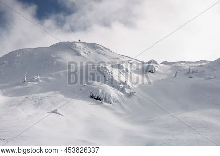 View Of Snow-capped Mountain Against The Backdrop Of The Sky With Man On Top