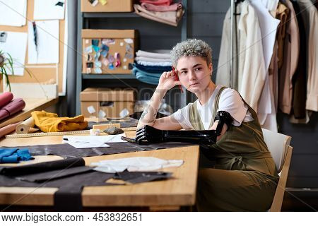Young Serious Self Employed Female Fashion Designer With Partial Arm Thinking Of New Ideas While Sit