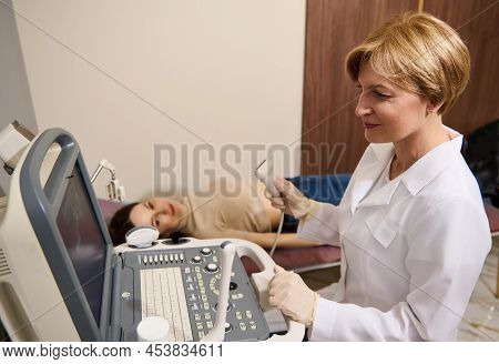 Mature Pretty Woman Radiologist Doctor Holds An Ultrasound Probe In One Hand And Looks At The Monito