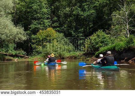 Family Kayak Trip. Man And Woman And Elderly Couple Senior And Seniora Rowing Boat On The River, A W