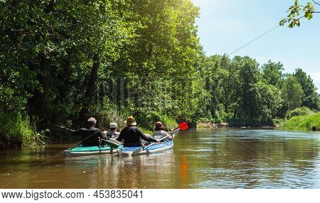 Family Kayak Trip. Man And Woman And Elderly Couple Senior And Seniora Rowing Boat On The River, A W