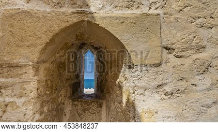 A Fragment Of The Ancient Citadel Of Qaitbay. A Thick Stone Wall With A Rough Surface. Through A Nar