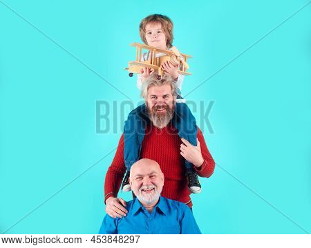 Boy Son With Father And Grandfather With A Toy Airplane Plays On Isolated Background. Family Adventu