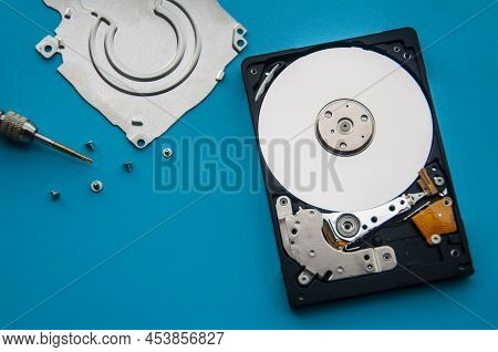 The Abstract Image Of Inside Of Hard Disk Drive On Blue Cover And Screw Driver Background. Concept O