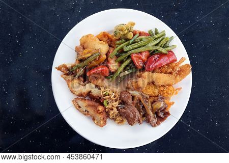 Chinese Food, Various Meat And Vegetables With Fried Rice And Sauce On A White Plate And A Dark Tabl