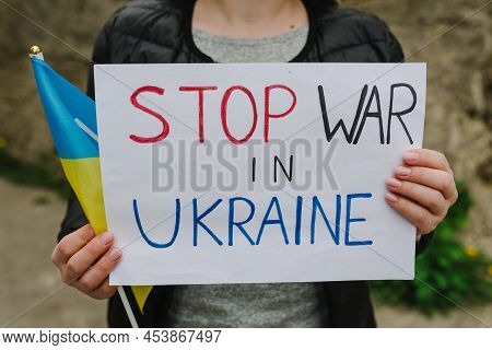 Stop War In Ukraine. Woman Calls No War, Raises Banner With Inscription Stop War. Girl Holds Blue-ye