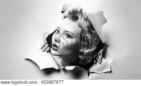 View Of Female Face Through Hole In Gray Paper. Surprised Woman Making Hole In Paper. Copy Space For