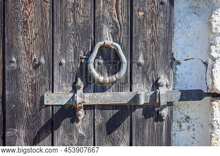 An Old Wrought Iron Door Knocker, A Metal Latch And A Lock On An Old Wooden Door In The Russian Styl