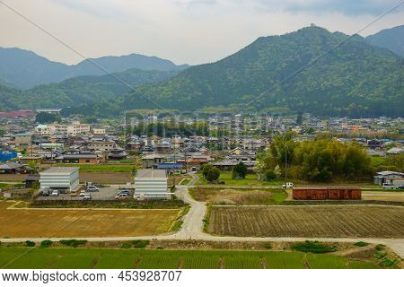 Empty T-intersection At Road Next To Small Country Village With Mountains In Background