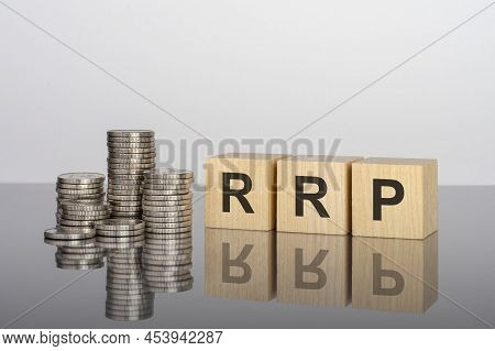 Rrp. Wooden Cubes. Blocks Lie On A Black Background. Stacks With Coins. Inscription On The Cubes Is 
