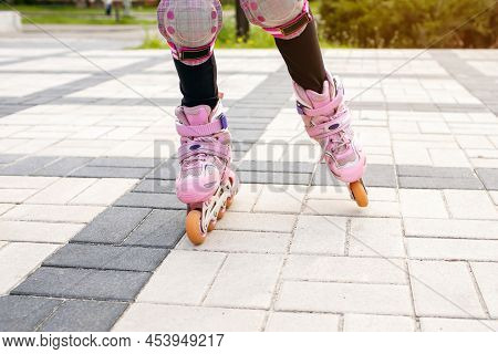 The Girl Rides On Pink Roller Skates With A View Of Her Legs. Part Of The Body In The Form Of Legs W