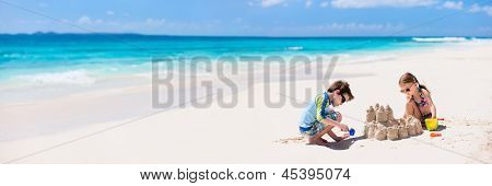 Bruder und Schwester machen Sandburg am tropischen Strand