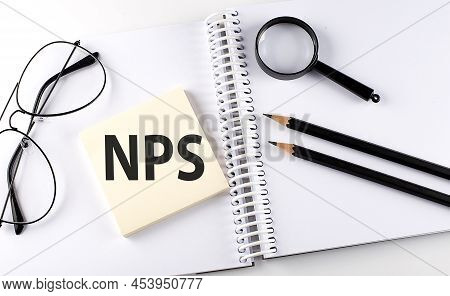Word Nps On The Sicker On A Notebook With Pencils,magnifier And Glasses