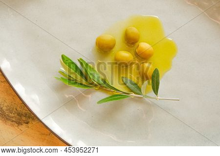Olives And Olive Oil.green Olives And Olive Branch In Olive Oil In A Ceramic Plate Close-up On A Nat