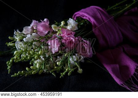 Pretty Pink And White Flowers Wrapped In Pink Pashmina Laying On Black Textured Background. Closeup 