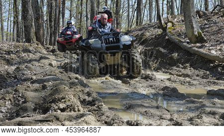 A Group Of Atvs Rides Through The Mud In The Spring Forest. Extreme Type Of Outdoor Activities. Quad