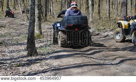 Rear View Of A Group Of Atv Riders Driving Along A Forest Dirt Road. Extreme Type Of Outdoor Activit
