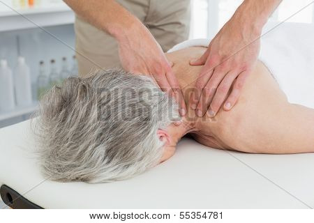 Close-up of a physiotherapist massaging a senior woman's back in the medical office