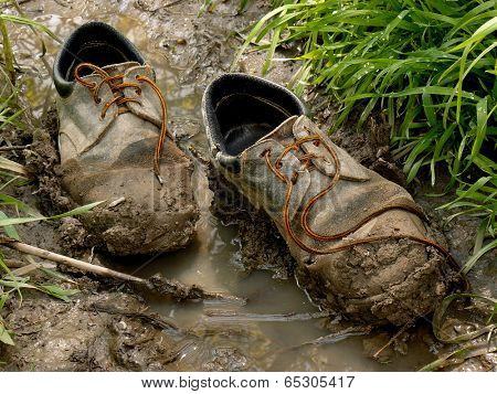 muddy worn out shoes in the puddle