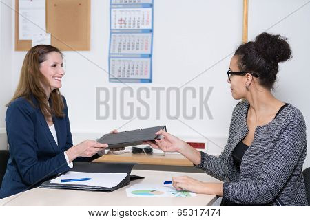 Business Woman Is Handing Over A File To Another Woman