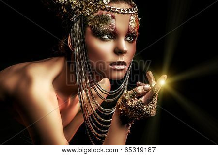 Art project: beautiful woman with golden make-up. Jewelry, make-up. Fashion. Over black background.