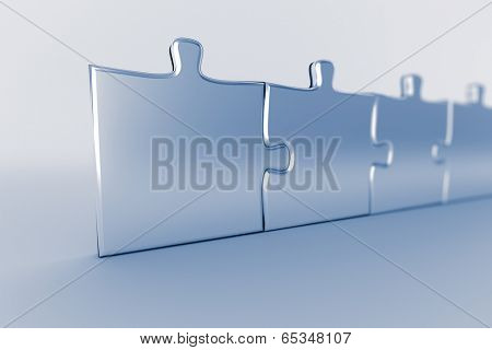 Row of connected puzzle pieces with blue tint and shallow depth of field