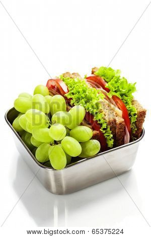 Lunch box with sandwich and grapes on white background