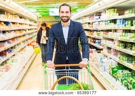 Man driving shopping cart while grocery shopping in supermarket 