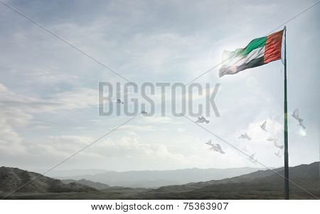 A massive flag of UAE flying against a horizon of Hajjar mountains, Fujeirah, UAE.