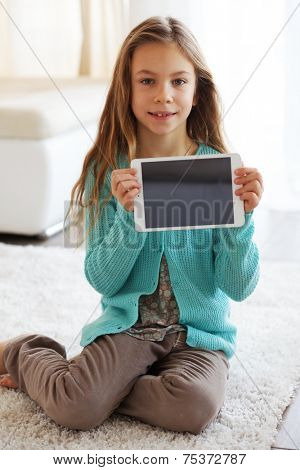 Child playing on ipad tablet pc sitting on a carpet at home