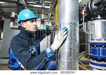 industrial construction worker at boiler room pipe heat insulation work