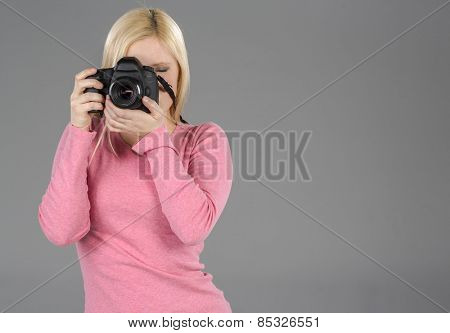 Blonde model holding a camera in a studio environment