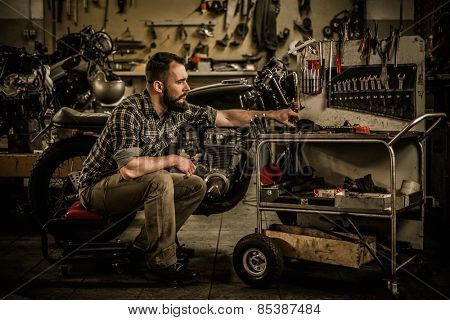 Mechanic building vintage style cafe-racer motorcycle  in custom garage