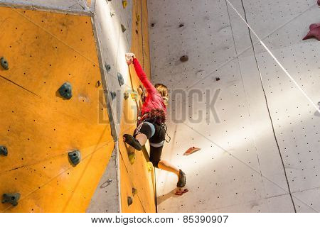 active young woman on rock wall in sport center.