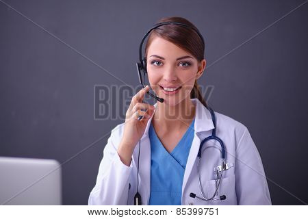 Doctor wearing headset sitting behind a desk with laptop