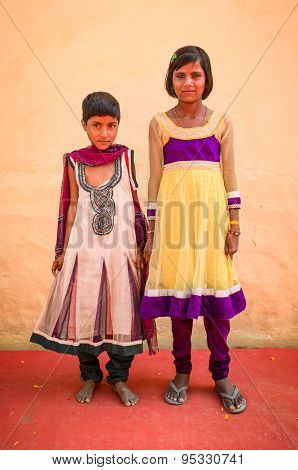 GODWAR REGION, INDIA - 15 FEBRUARY 2015: Two Indian girls wear beautiful dresses and pose in front of wall on red carpet during wedding.