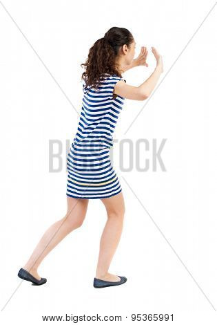 back view of woman pushes wall. Isolated over white background. Rear view people collection. backside view of person. African-American woman in a striped dress in barely pushes something on my own.