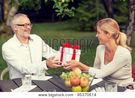 family, happiness, generation, home and people concept - happy family with gift box having holiday dinner outdoors