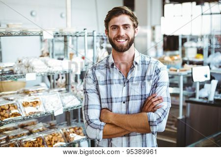 Selfassured waiter smiling in front of his bakery