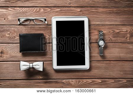 Tablet pc computer wallet eyeglasses bowtie and wristwatch on table