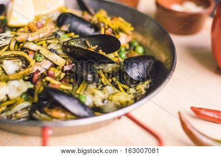 Italian pasta fideua with seafood, oysters, black pasta