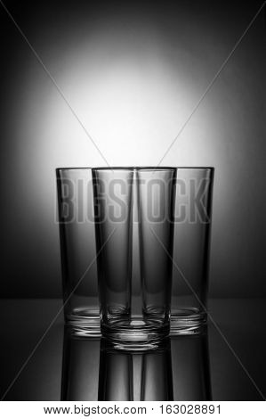 Three empty glasses on a blackand white background with reflection
