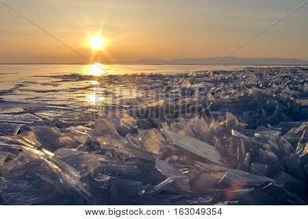 Sunset on Lake Baikal in winter. Ice hummlocks and icicles on foreground.
