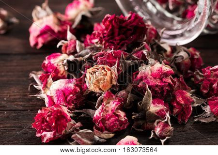 Rose Petals And Dried Flowers In Jar On Old Wooden Table. Healthy Concept
