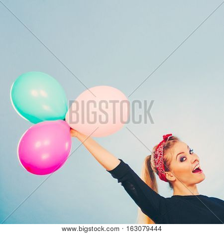 Craziness and lots of fun. Cute crazy joyful girl playing with colored balloons. Blonde playful retro style woman feel craze.