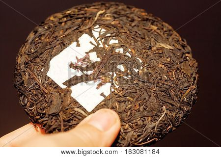 Tea Pu-erh in shape of cake traditional chinese drink. Popular antioxidant tea from China in the hand of person.